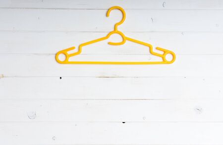 yellow plastic clothes hanger on white wooden backgroundの写真素材