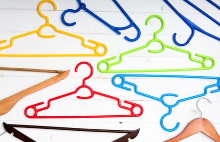 many different clothes hangers on white wooden backgroundの写真素材