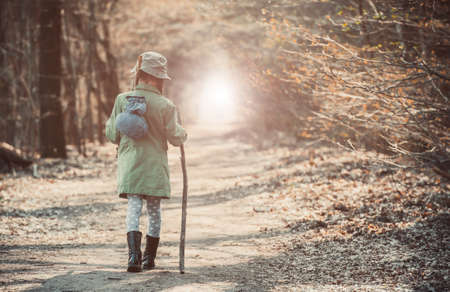 little girl goes on a footpath in the forest photo in retro styleの写真素材