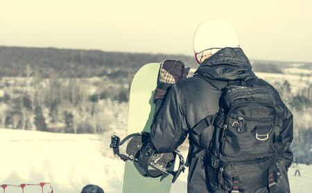 people in ski suit holding snowboards on a snowhill view from backの写真素材