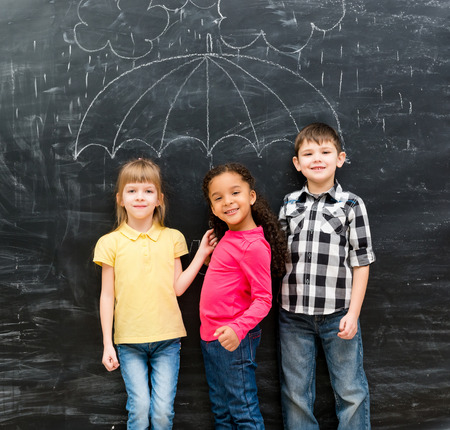 three funny laughing children with umbrella drawn on the blackboard on backgorundの写真素材
