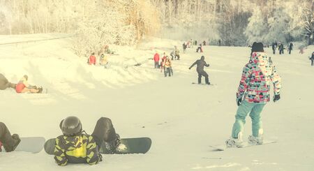 people on snowboards watching snowboarders on backgroundの写真素材