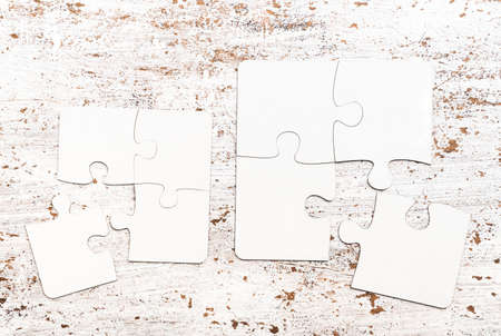 different size pieces of white puzzle on a table with cracked paintの写真素材