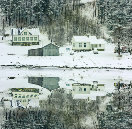 wooden houses on the banks of the Norwegian fjord with reflection in waterの写真素材