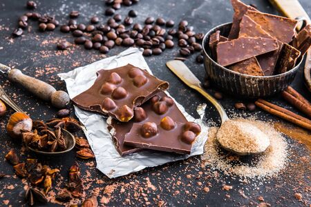 Chocolate with nuts and spices in the spoons on a dark tableの写真素材