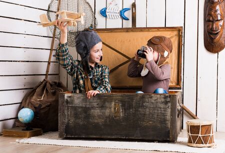 sisters playing with wooden plane in chestの写真素材