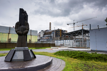 monument to the Chernobyl catastrophe liquidators with fourth reactor on the backgroundの写真素材