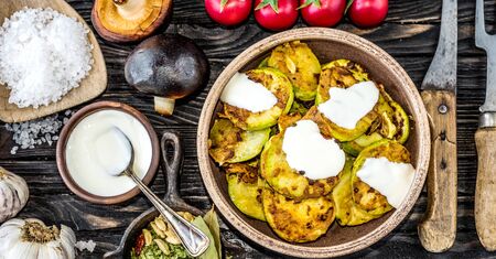 fried zucchini with sour cream and spices on wooden table, top viewの写真素材