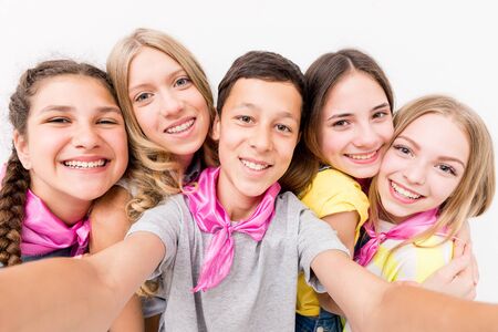 teenage smiling boy making selfie with cute funny girls