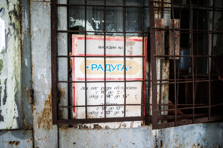 Pripyat, Ukraine - May 29, 2016: store window with sign board behind rusty grating in Pripyat, Chernobyl, Ukraineのeditorial素材