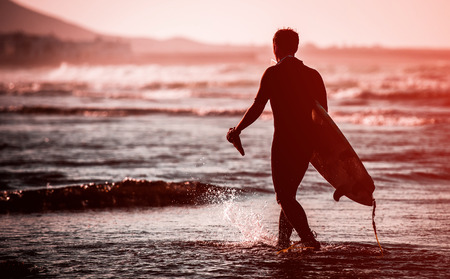 Silhouette of man with a surfboard on the beachの写真素材