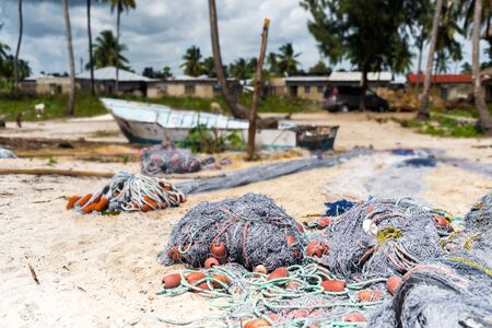 landscape with fishing nets and boat on a beach with houses on the background in Zanzibarの写真素材