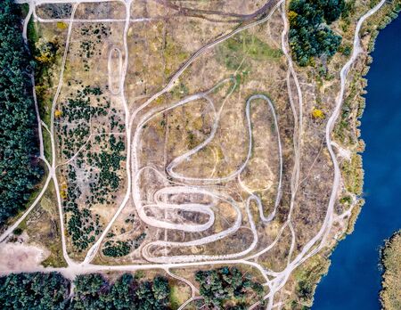 top view of tracks in a suburb field with grove and water on its side, aerial photo