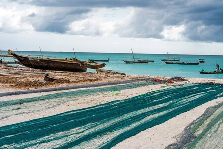 large fishing nets lying on african beach with boats near the shore on the backgroundの写真素材