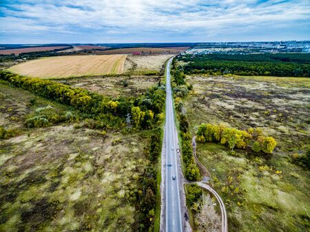 beautiful colorful fall landscape of suburb field with track and trees on its sides, aerial photoの写真素材