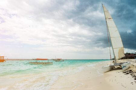 Modern expensive catamaran vessel sitting right next to the shore of oceanの写真素材