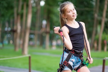 Cute teenage girl in safety harness on her belt in rope parkの写真素材