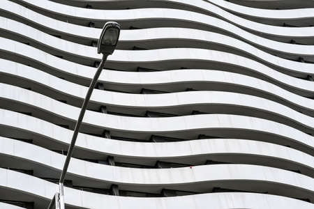 Curved facade of grey building with a street light on the foregroundの写真素材