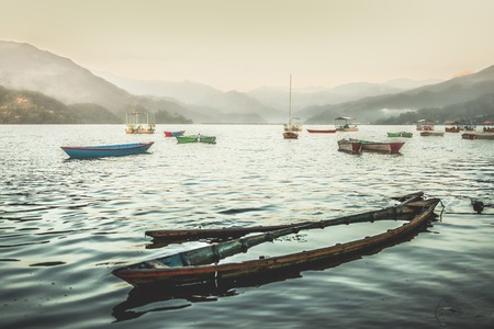 Colorful boats on Phewa lake at sunset. Sunk boat on the foreground.の写真素材