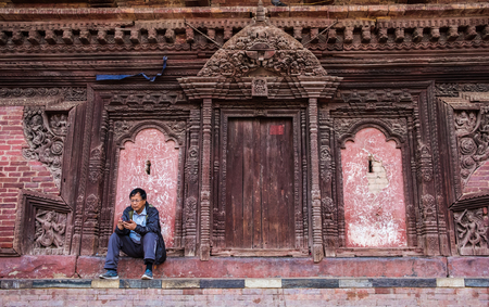 Kathmandu, Nepal, - October 05, 2017: Man sitting near the Wall of traditional Nepalese temple in The centrum of Kathmanduのeditorial素材