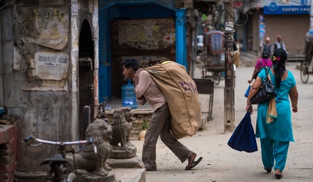 Kathmandu, Nepal - 06 October 2017: man carry heavy sack on his back on Kathmandu streets, Nepal