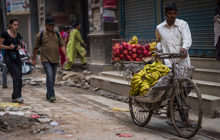 Kathmandu, Nepal - October 05, 2017: Man sells bananas and apples on a bike on a street marketのeditorial素材