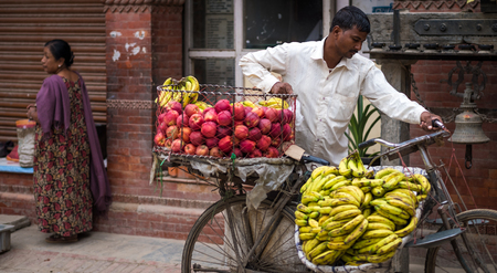 Kathmandu, Nepal - October 05, 2017: Man sells bananas and apples on a bike on a street marketのeditorial素材