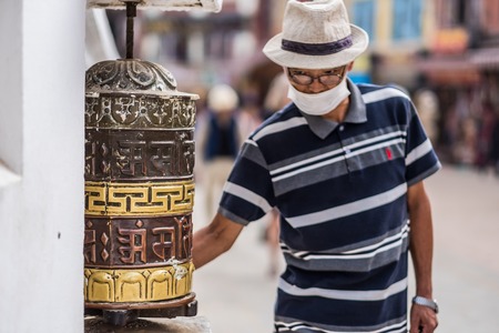Kathmandu, Nepal - 06 October 2017: Prayer wheels and man who pray at Boudhanath Stupa in Kathmandu, Nepalのeditorial素材