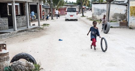 Zanzibar, Tanzania - July 14, 2016: Children in Zanzibar, Tanzania playing with tires outside, vehicles on the backgroundのeditorial素材