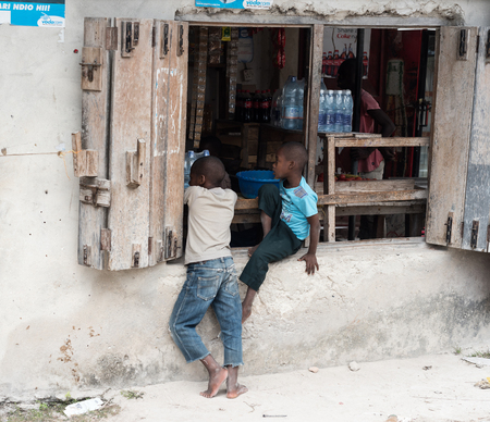 Zanzibar, Tanzania - July 14, 2016: Local children in Zanzibar, Tanzania, playing near a failed store with heavy shuttersのeditorial素材