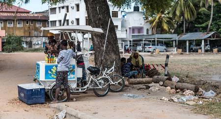 Zanzibar, Tanzania - July 15, 2016: Young muslim boy living on zanzibar selling sparkling water, street trade and ruined buildingsのeditorial素材