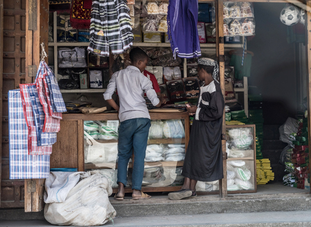 Zanzibar, Tanzania - July 15, 2016: Street trade on zanzibar, two boys selling clothing and garments for muslim people, tanzaniaのeditorial素材