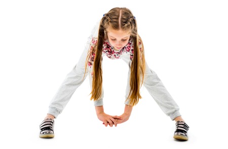 Little girl do forward bend exercise in grey sportwear, isolated on white background. Healthy lifestyleの写真素材