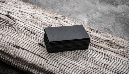 Stack of black blank name cards on wooden background. Mockup for branding company style.の写真素材