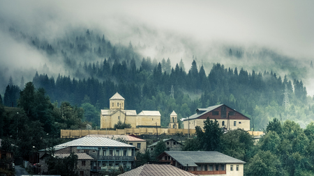 View on the church against forest in fog, Mestia, Georgia. Saint Nicholas church in Mestiaの写真素材
