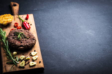 Homeemade beef burger cutlet with herbs and spices on wooden cooking board. Space for textの写真素材