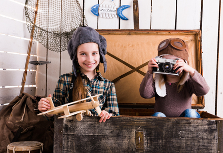 two little girls-pilots in big wooden chest playing camera and wooden planeの写真素材