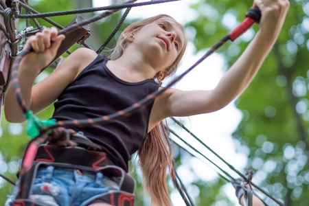 Teenage girl hiking in the rope park in safety equipment. Safety harness.の写真素材