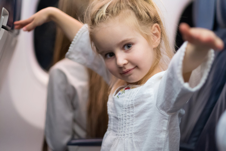 Happy blond young girl in white blouse travelling by plane.の写真素材