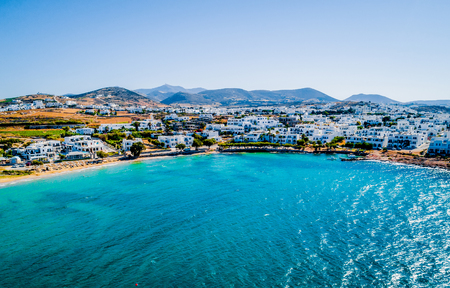 Aerial bird's eye view of a Greek turquoise bay and the whitewashed traditional houses on the coastline and mountains on the backgroundの写真素材