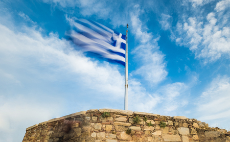 Greek national flag on flagpole waving against blue sky, Acropolis, Athens, Greeceの写真素材