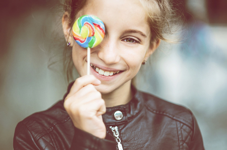 Beautiful little girl with candy, outdoorの写真素材
