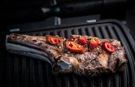 Grilled bone-in ribeye beef steak with chili pepper on pan grill, top view. Homemade meat grillの写真素材