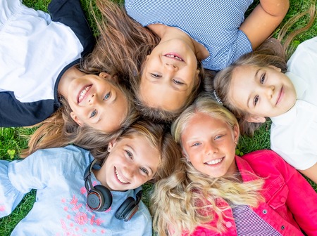Happy smiling kids looking at the camera on the grass, topview