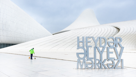 Baku, Azerbaijan - January 01, 2018: Cleaner in bright uniform tidy up teritory of Heydar Aliev Center, Baku, Azerbaijanのeditorial素材