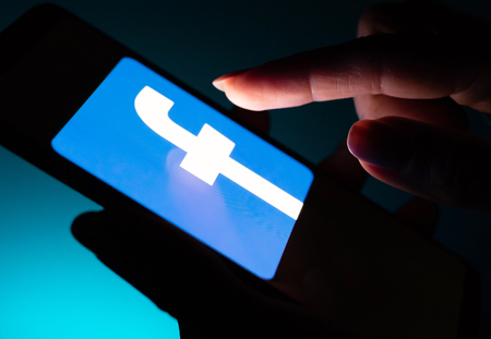 Kharkiv, Ukraine - 16 November 2018: close up smartphone with Facebook app on the screen with a dark backgroundのeditorial素材