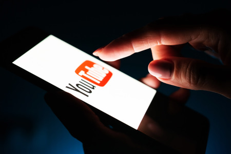 Kharkiv, Ukraine - 16 November 2018: close up girl hand using smartphone with youtube app on the screen with a dark backgroundのeditorial素材