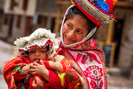 Peru, Cusco - 13 October 2018: Mother in national colorful clothing holding little kid