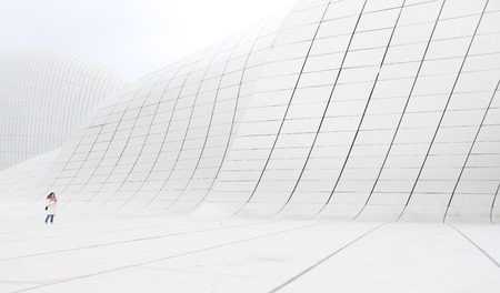 Baku, Azerbaijan - January 01, 2018: Girl in white clothes standing on the white curved wall of modern Heydar Aliev Center, Baku, Azerbaijanのeditorial素材