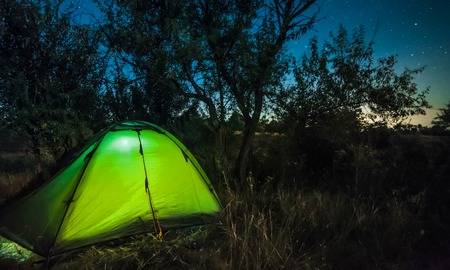 Bright illuminated tourist tent under amazing night starry sky